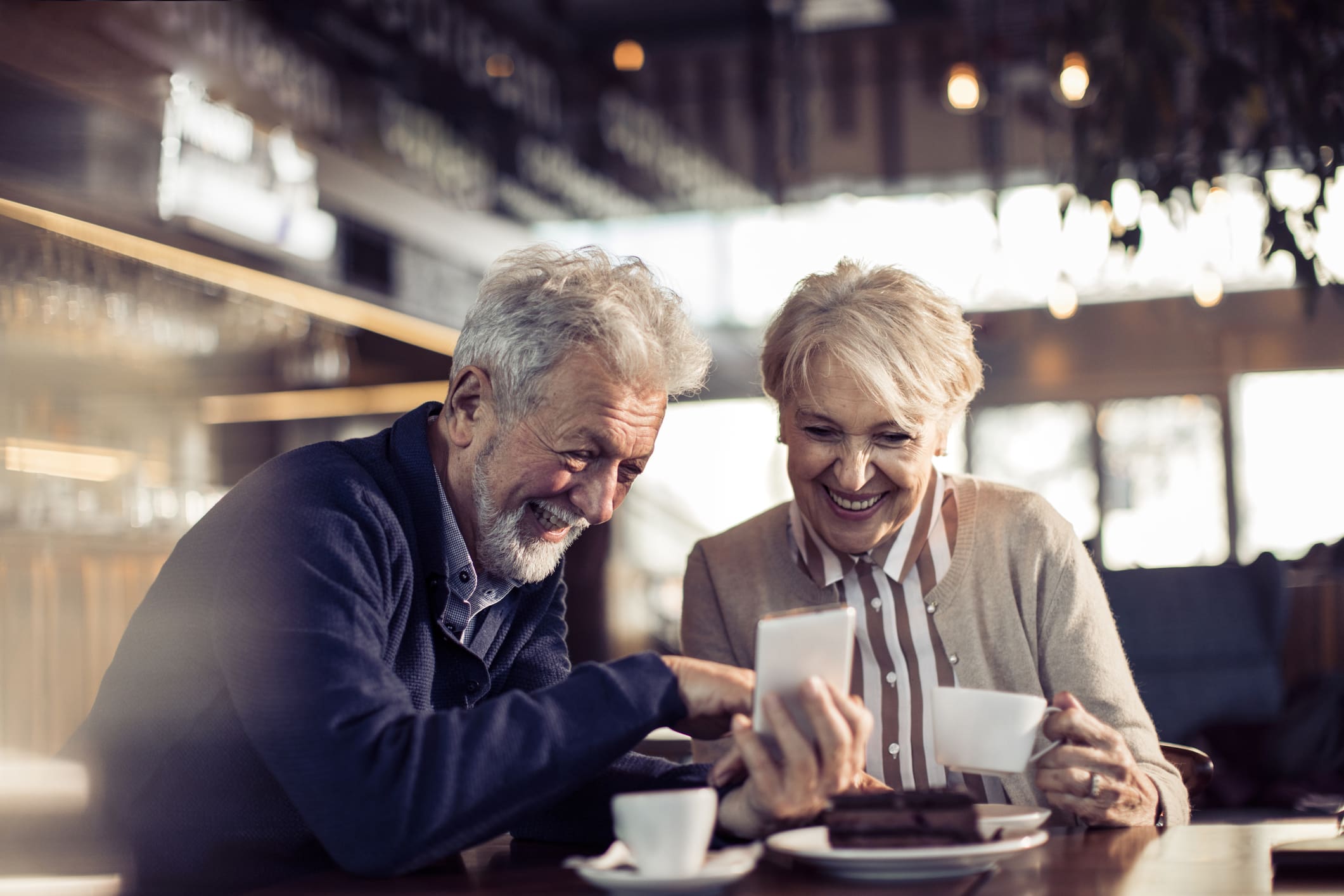 Elderly couple with hearing loss looking at photos, communicating, listening to one another
